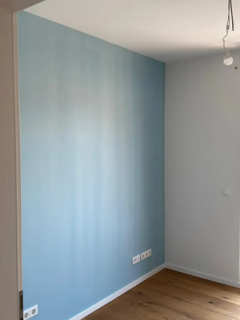 Eine frisch gestrichene hellblaue Wand in einem hellen Raum, umgesetzt von RoGi-Bau.