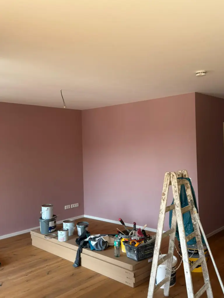 Ein Raum mit frisch gestrichenen braunroten Wänden und Malerwerkzeug beim Innenausbau durch RoGi-Bau.