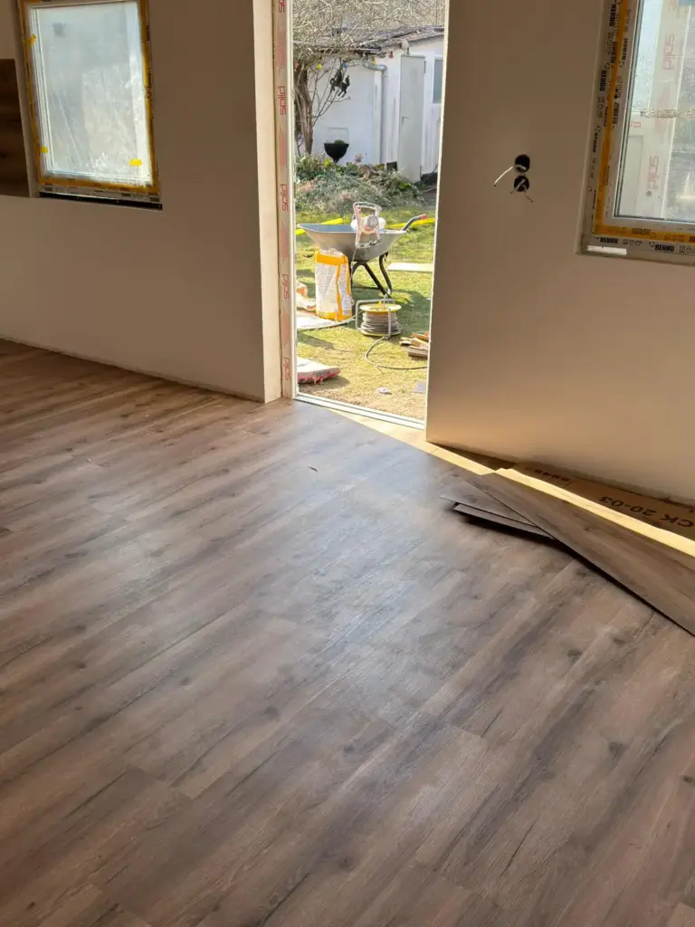 Ein frisch verlegter Laminatboden in einem hellen Raum mit weißen Wänden, umgesetzt durch RoGi-Bau.