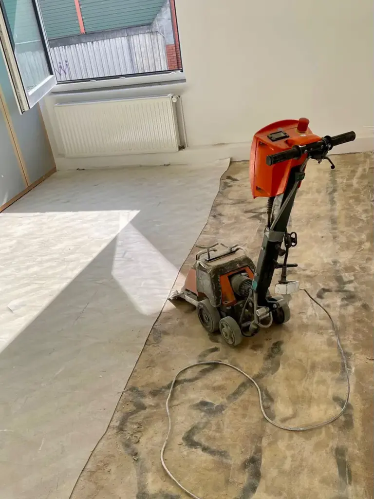 Ein Raum mit einer Baumaschine, in dem gerade von RoGi-Bau Bodenbelag verlegt wird.