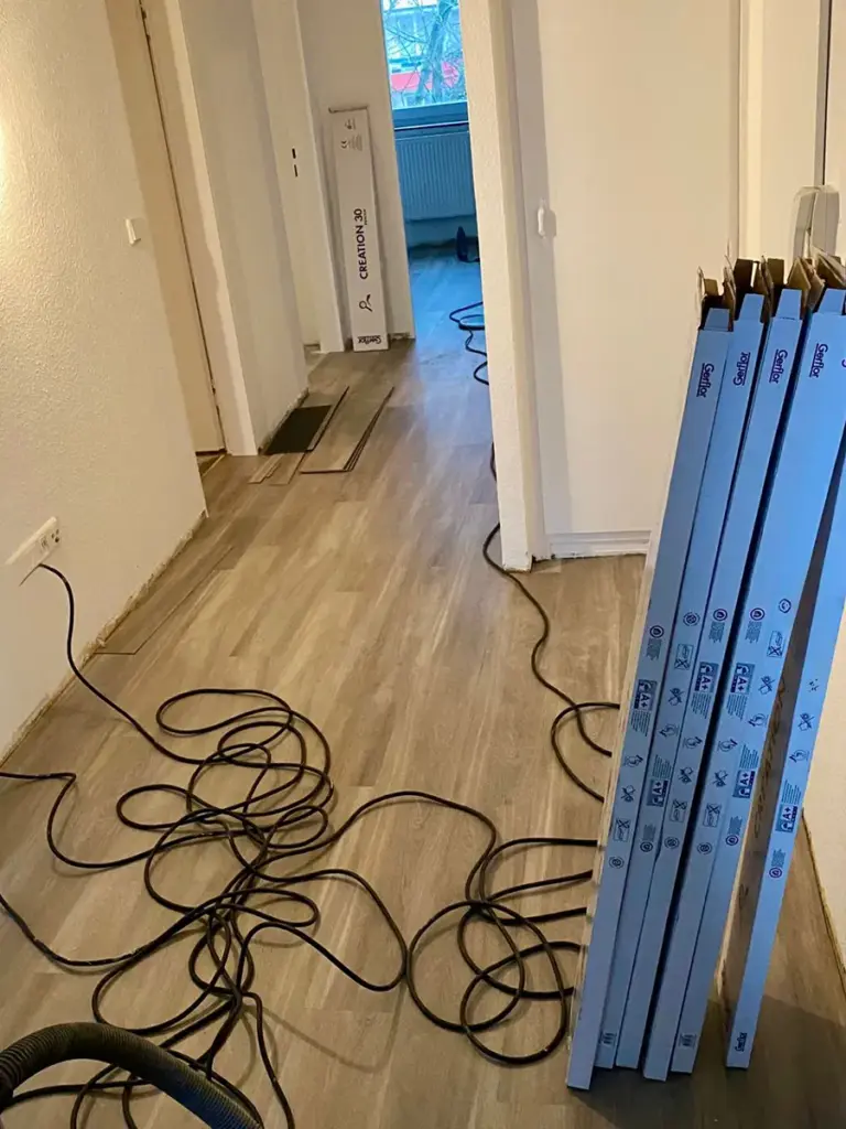 Innenraum beim Verlegen von Bodenbelag mit auf dem Boden liegenden Kabeln, umgesetzt von RoGi-Bau.