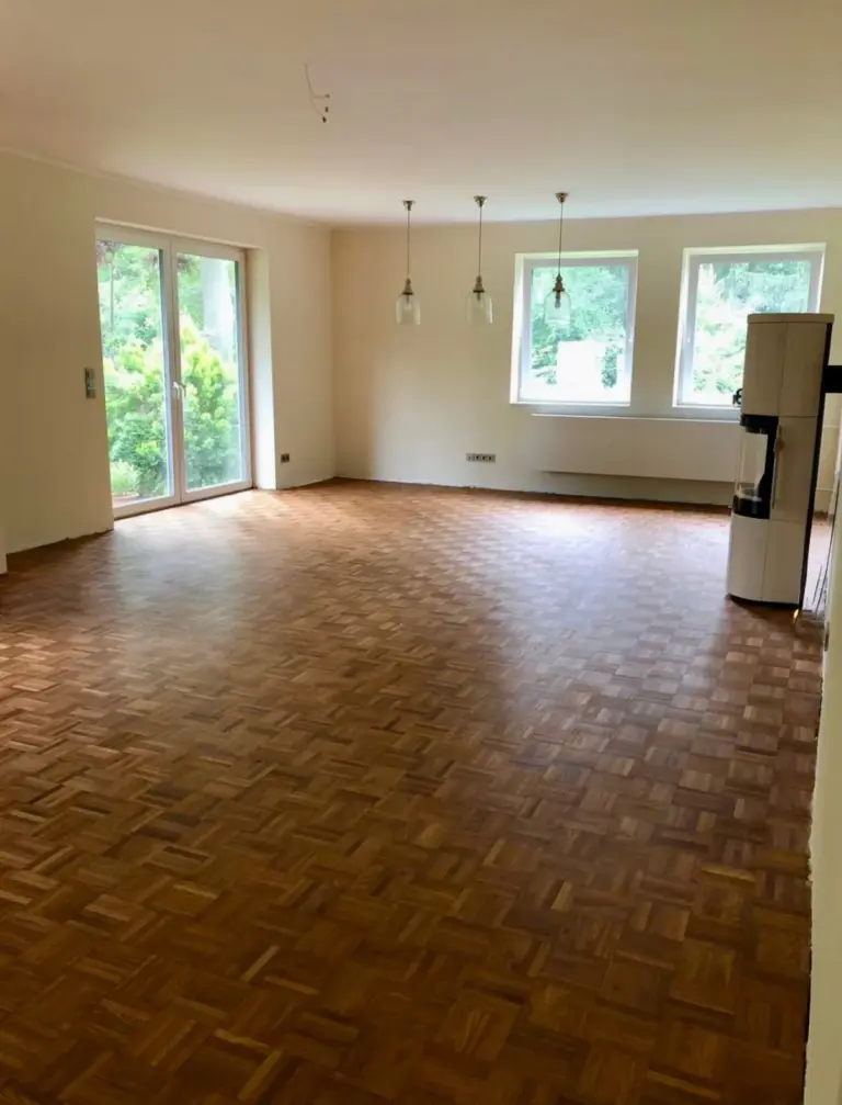 Ein großer Wohnraum mit Holzboden und frisch gestrichenen weißen Wänden, umgesetzt von RoGi-Bau.