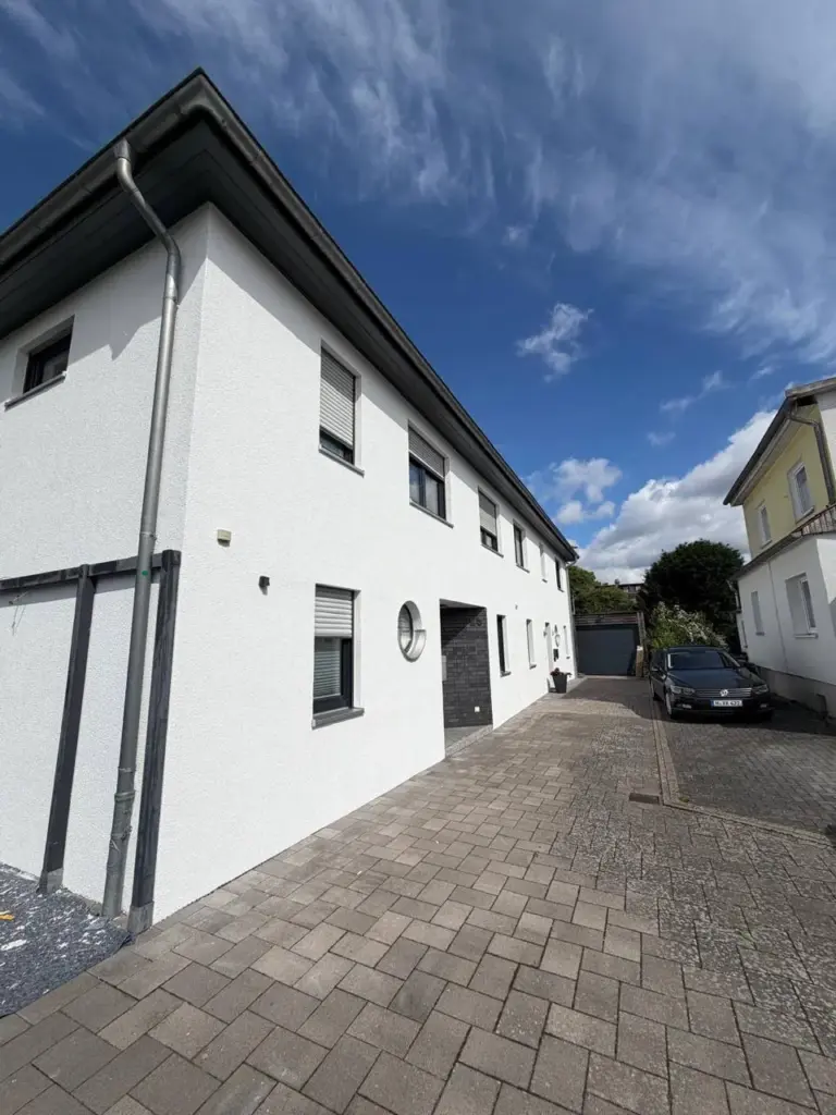 Die Außenfassade eines frisch renovierten weißen Hauses mit Hof.