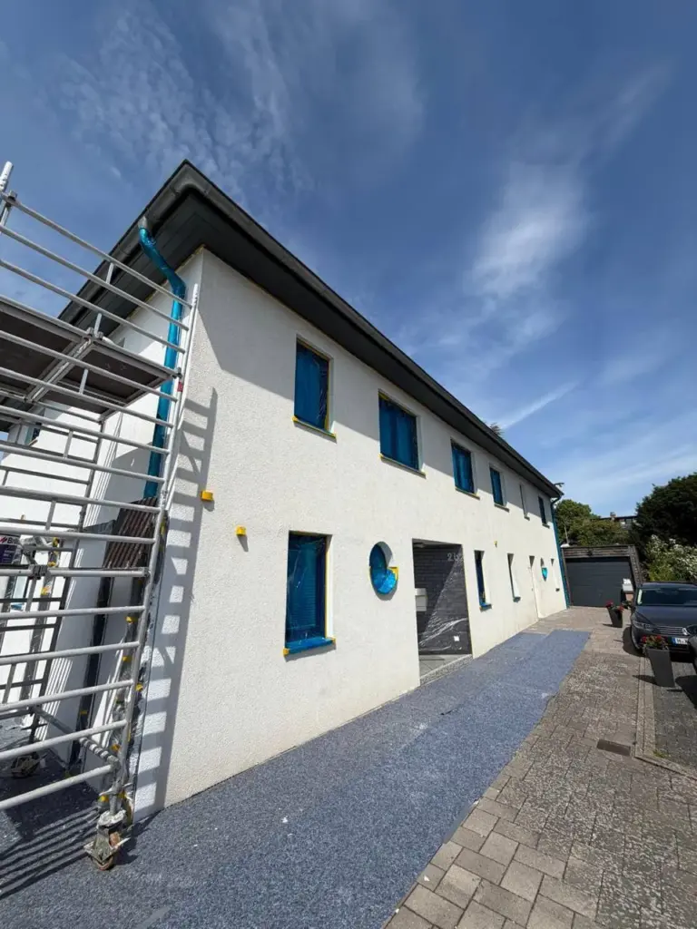 Die Außenfassade eines weißen Hauses mit Hof, das gerade renoviert wird.