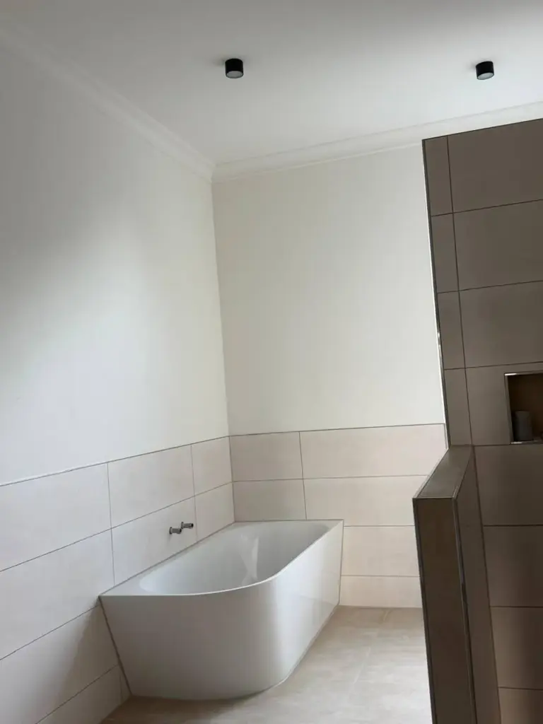 Ein von RoGi-Bau frisch renoviertes Bad mit Badewanne und beige-weißen Fliesen.