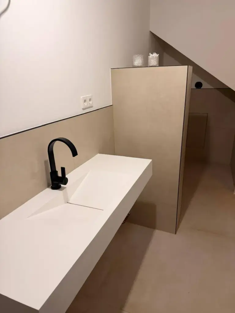 Ein von RoGi-Bau frisch renoviertes Bad mit Waschbecken und beige-weißen Fliesen.