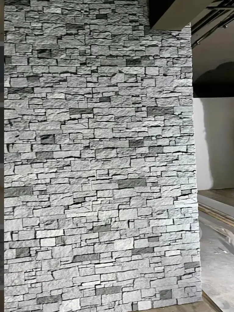 Eine Wohnwand mit hellgrauen Steinplatten in voller Höhe, umgesetzt von RoGi-Bau.